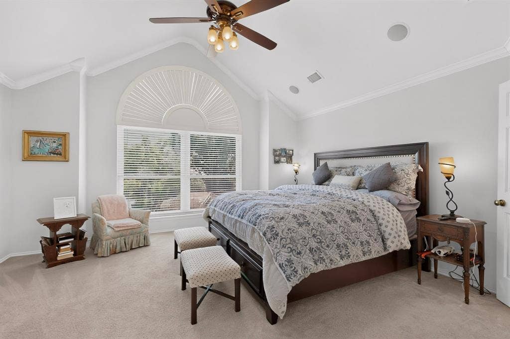 3820 Nash Lane, Plano, TX 75025 Vaulted ceiling with crown molding, ceiling fan with integrated lighting, arched window with horizontal blinds, carpeted flooring, and built-in ceiling speakers