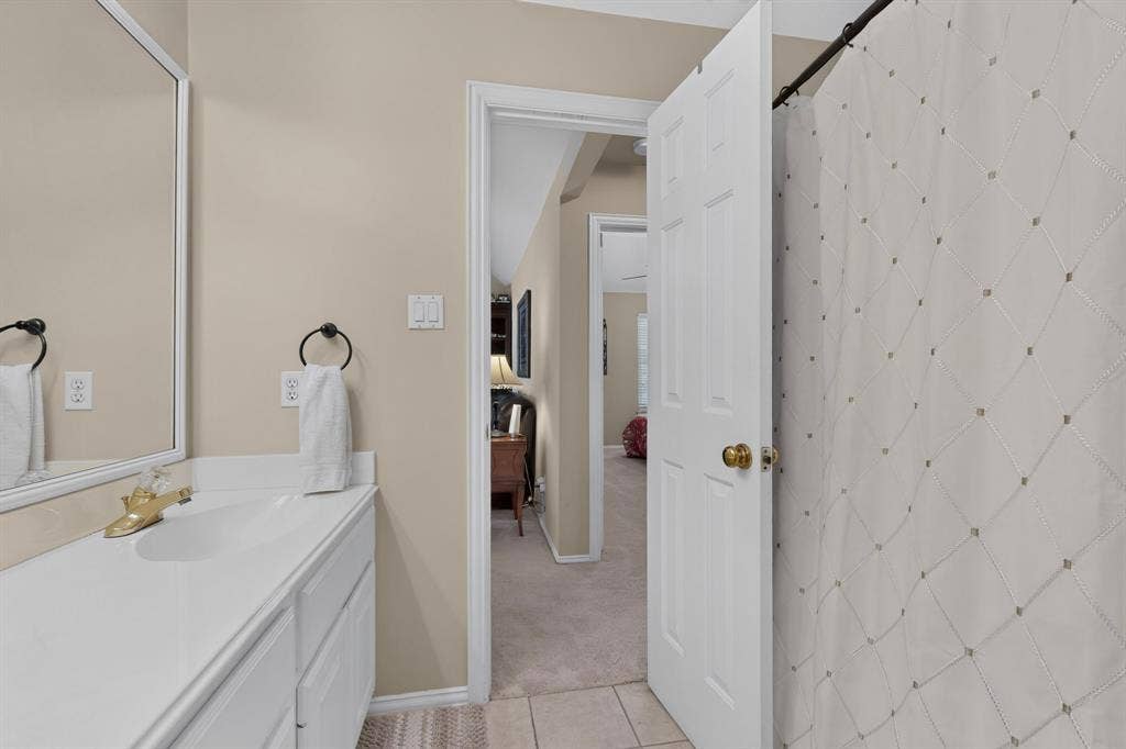 3820 Nash Lane, Plano, TX 75025 White vanity with integrated sink, framed mirror, and brushed brass faucet