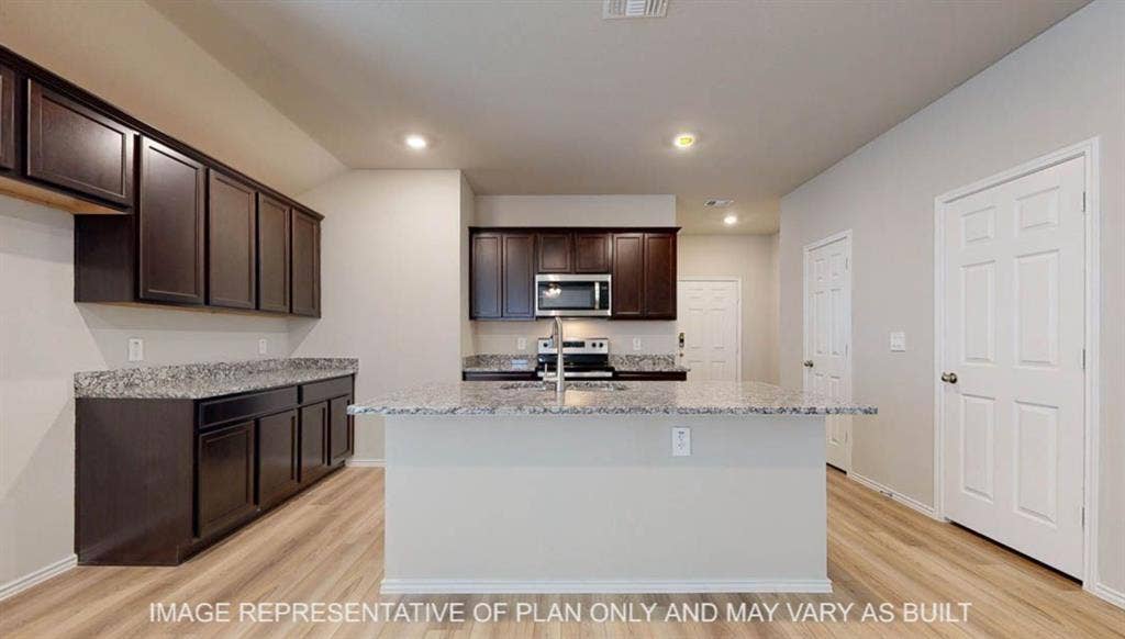 3016 Cyprian Road, Lorena, TX 76655 Kitchen featuring a central island, dark wood-finish cabinetry, light-toned countertops, stainless steel appliances, and wood-finish flooring