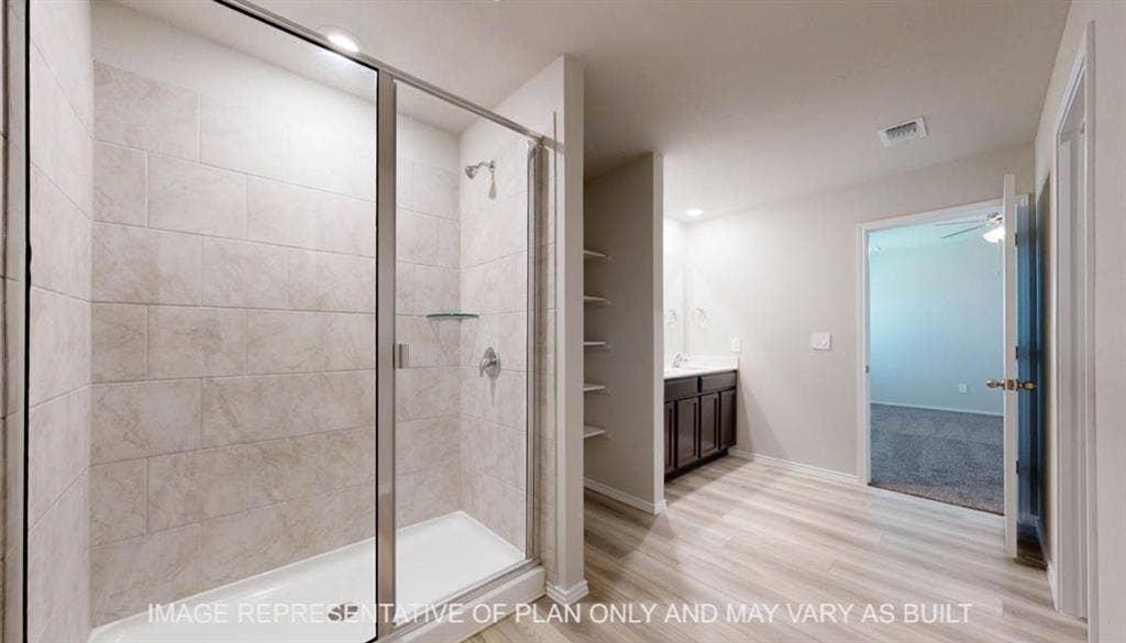 3016 Cyprian Road, Lorena, TX 76655 Walk-in shower with glass enclosure and tiled walls, wood-finish flooring, built-in shelving, and a vanity with dark wood-finish cabinetry