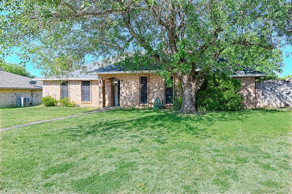 1223 Sequoia Drive, DeSoto, TX 75115 Brick exterior featuring an arched entry, mature trees, and a spacious front lawn