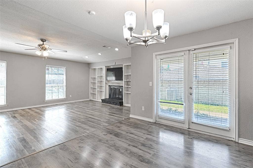 1223 Sequoia Drive, DeSoto, TX 75115 Spacious room with wood-finish flooring, a built-in fireplace with shelving, and double glass panel doors
