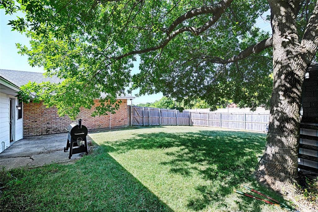 1223 Sequoia Drive, DeSoto, TX 75115 Expansive backyard with a manicured lawn, established shade tree, and wood privacy fencing