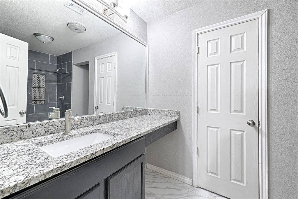 1223 Sequoia Drive, DeSoto, TX 75115 Built-in vanity with a rectangular undermount sink, stone-finish countertop, and brushed nickel faucet