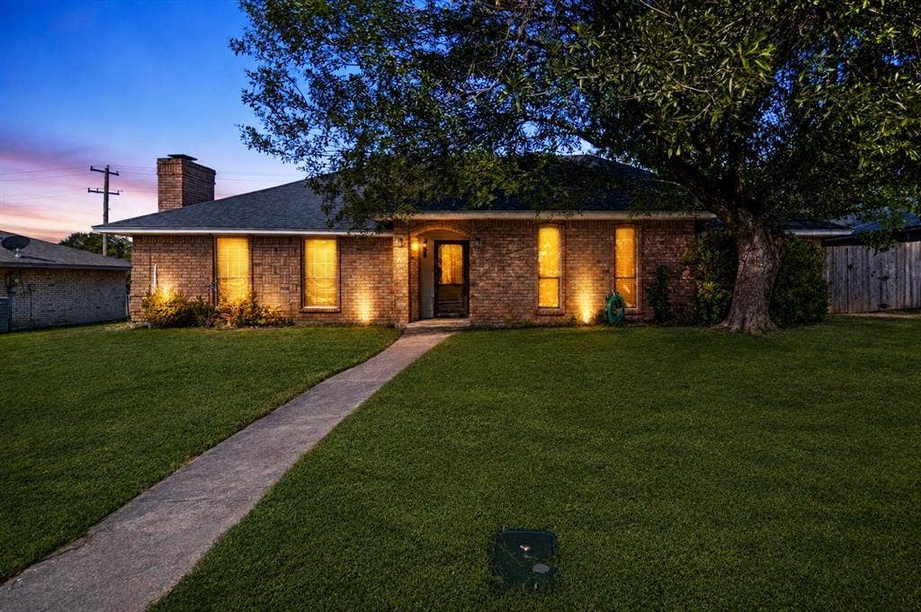 1223 Sequoia Drive, DeSoto, TX 75115 Brick exterior with a dark shingle roof, concrete walkway, and a manicured lawn