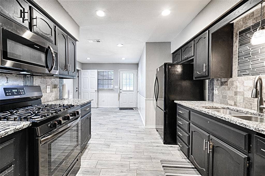 1223 Sequoia Drive, DeSoto, TX 75115 Kitchen featuring granite countertops, dark wood cabinetry, stainless steel appliances, and a tile backsplash
