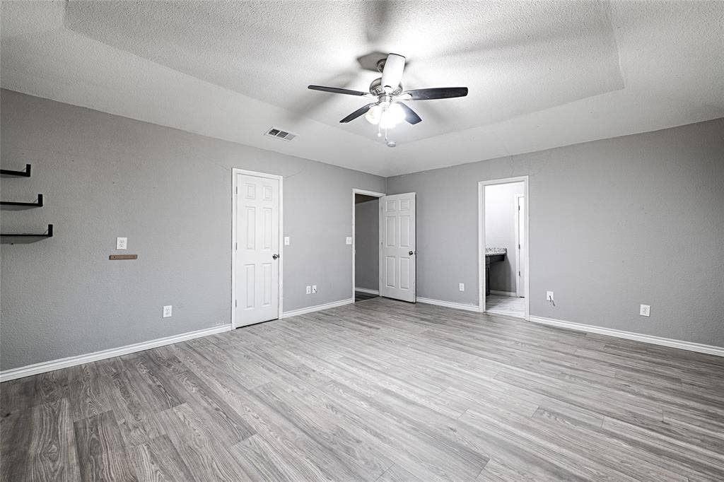 1223 Sequoia Drive, DeSoto, TX 75115 Tray ceiling with a ceiling fan, wood-finish flooring, light grey wall paint, and white trim