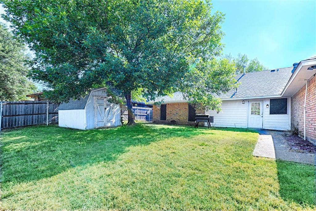 1223 Sequoia Drive, DeSoto, TX 75115 Expansive backyard with a large shade tree, wood privacy fencing, and a storage shed