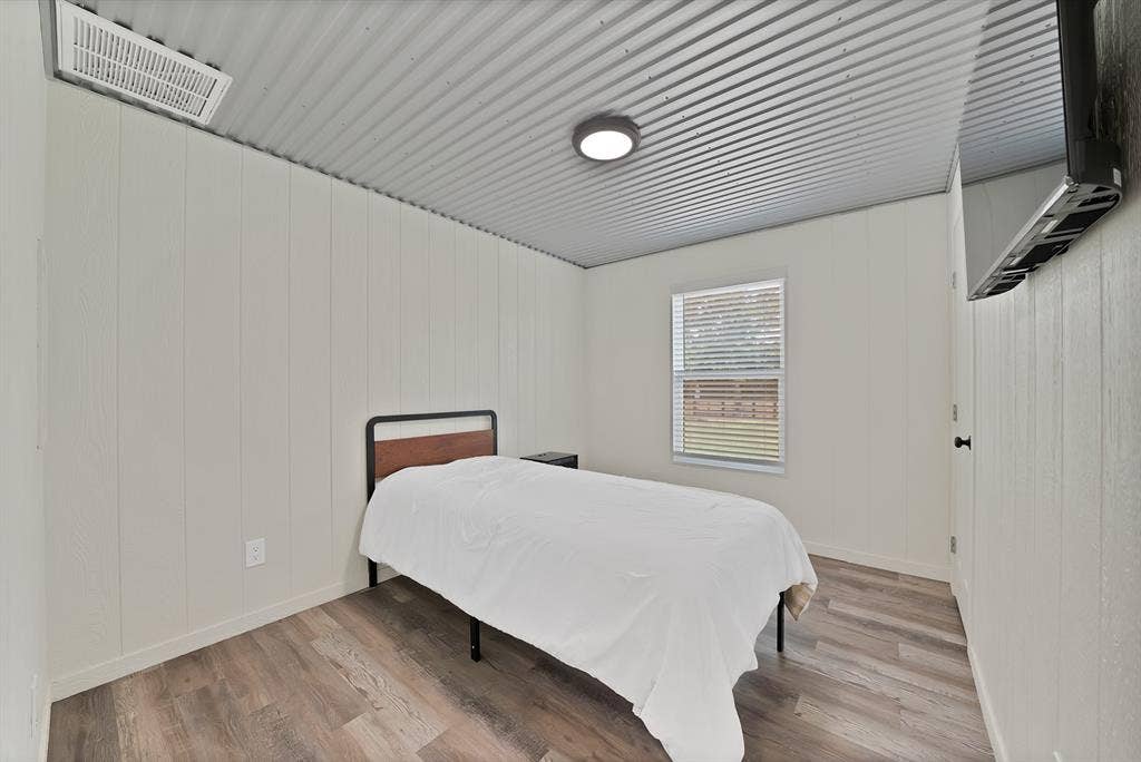 Wood-finish flooring, white panel walls, and a corrugated metal ceiling