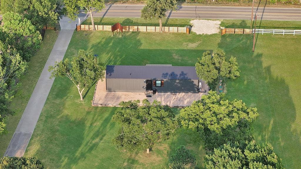 Expansive green lawn surrounds the property, featuring mature trees and a concrete driveway