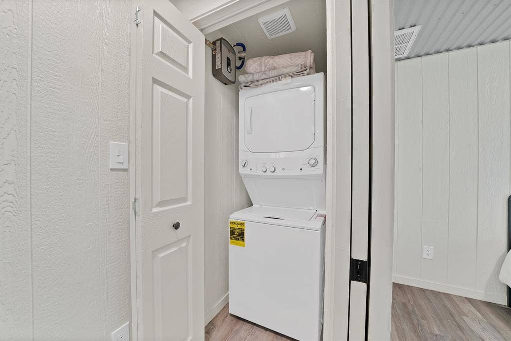 Closet laundry area featuring a white stacked washer and dryer unit, and paneled bifold doors
