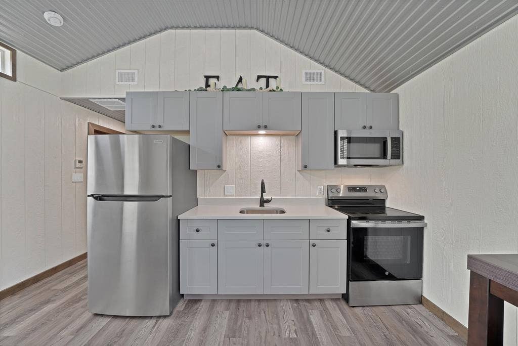 Kitchenette featuring stainless steel appliances, light gray cabinetry, white countertops, and wood-finish flooring