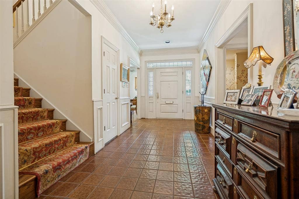 3418 Dartmouth Avenue, Highland Park, TX 75205 Inviting foyer featuring a chandelier, tile flooring, a paneled front door with sidelights, and a staircase with a decorative runner