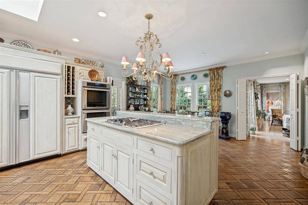 3418 Dartmouth Avenue, Highland Park, TX 75205 Kitchen featuring a central island with a gas cooktop, built-in double ovens, integrated refrigerator, wood-finish flooring, and decorative chandelier lighting