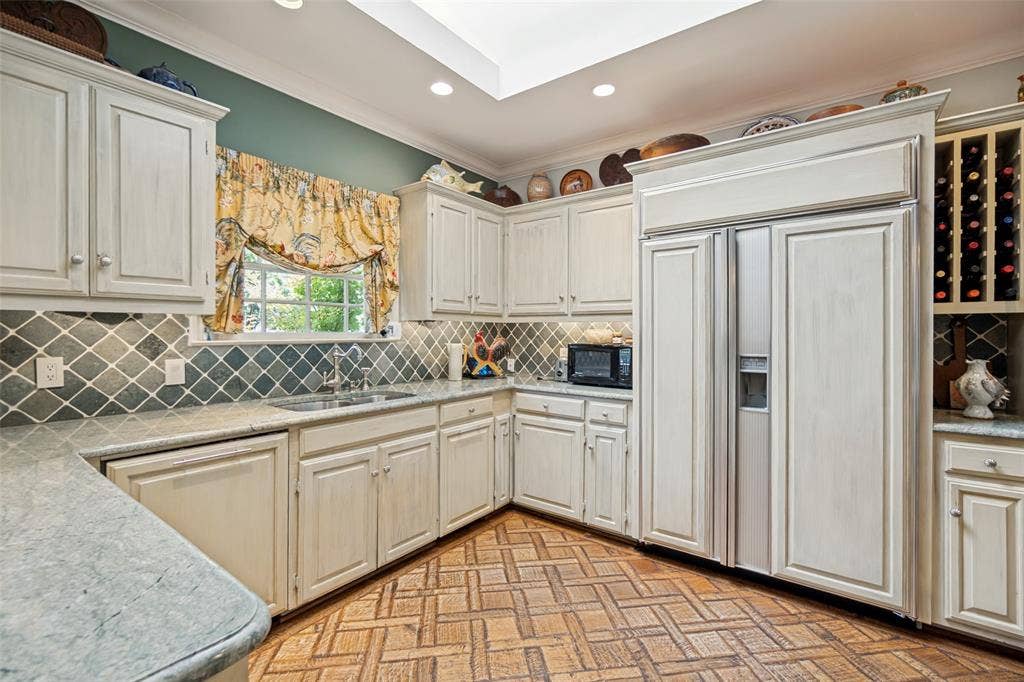 3418 Dartmouth Avenue, Highland Park, TX 75205 Kitchen featuring wood-finish flooring, light-toned cabinetry, light-toned countertops, a full-size stainless steel refrigerator, and a skylight