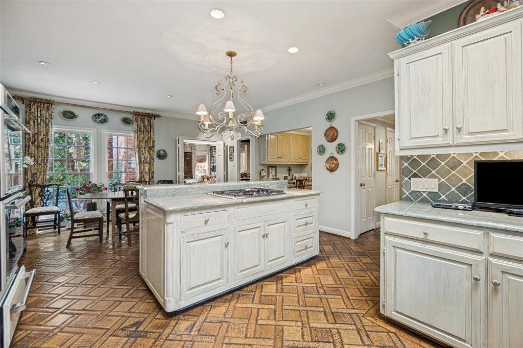3418 Dartmouth Avenue, Highland Park, TX 75205 Kitchen featuring a central island with cooktop, white cabinetry, integrated double oven, and patterned wood flooring