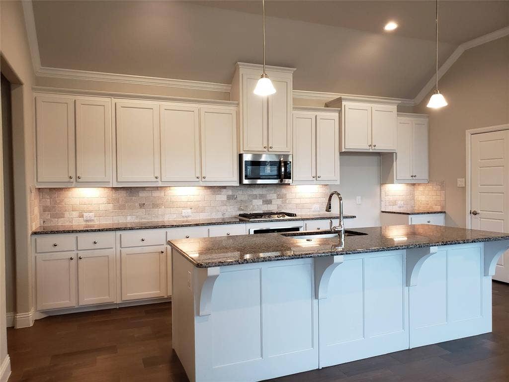940 Parkside Drive, Argyle, TX 76226 Kitchen featuring white cabinetry, dark stone countertops, tile backsplash, stainless steel appliances, and a central island with an undermount sink