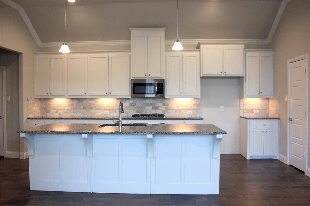 940 Parkside Drive, Argyle, TX 76226 Kitchen featuring white shaker cabinetry, granite countertops, tile backsplash, stainless steel microwave, and wood-finish flooring