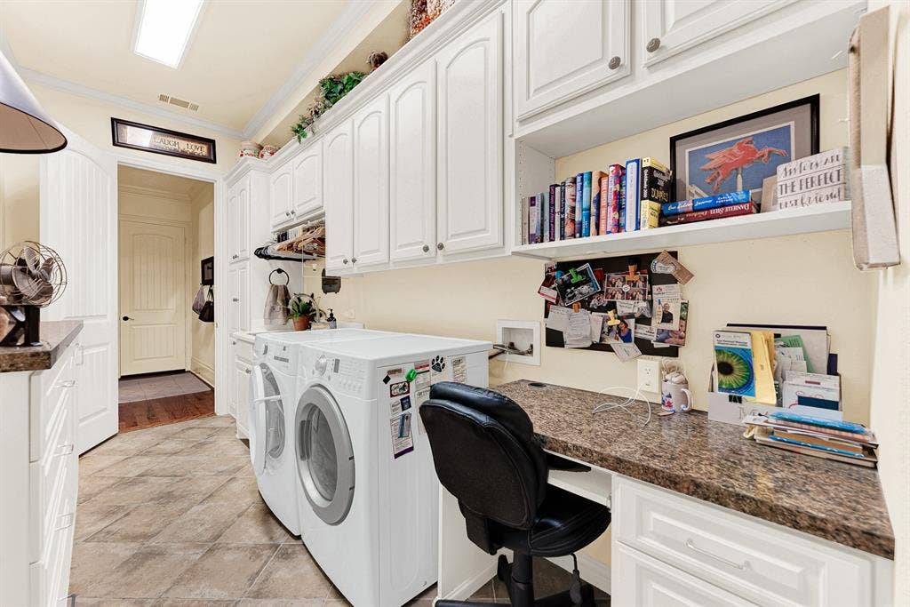7032 PORTOBELLO Drive, Plano, TX 75024 Bright white upper cabinetry and a long built-in desk stretch across durable tile flooring, illuminated by clean overhead lighting. Sit down to organize weekly schedules or manage family affairs in this quiet, efficient workspace.