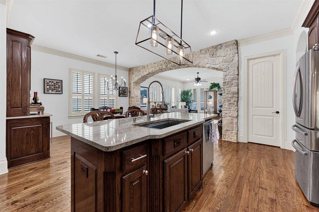 7032 PORTOBELLO Drive, Plano, TX 75024 An undermount basin and pro-style faucet anchor the granite prep surface, framed by the rustic stone arch backdrop. Chat effortlessly with loved ones across the room while washing fresh produce for supper.