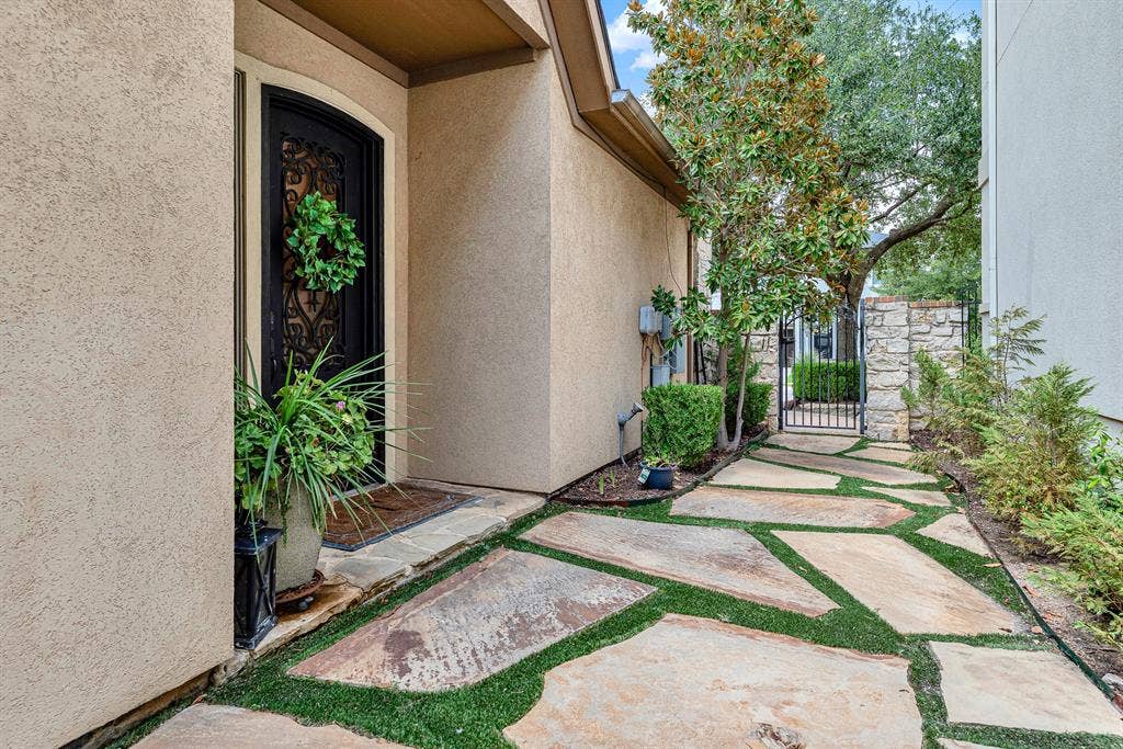 7032 PORTOBELLO Drive, Plano, TX 75024 A wrought-iron gate frames the walkway while tall alcove walls cast deep, cool shadows across the pathway. Picture welcoming close friends through this secret garden path as twilight sets in for an intimate evening dinner.