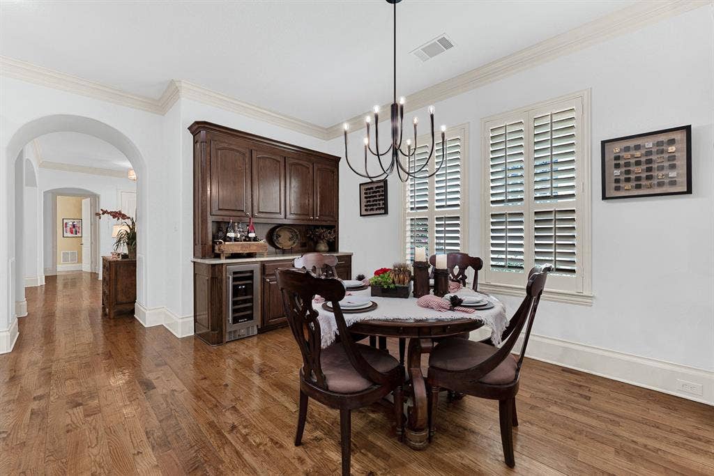 7032 PORTOBELLO Drive, Plano, TX 75024 Rich dark wood cabinetry frames a built-in wine cooler beneath custom plantation-shuttered windows. Pour a perfectly chilled glass of Pinot Noir while preparing an intimate dinner for two as night falls.