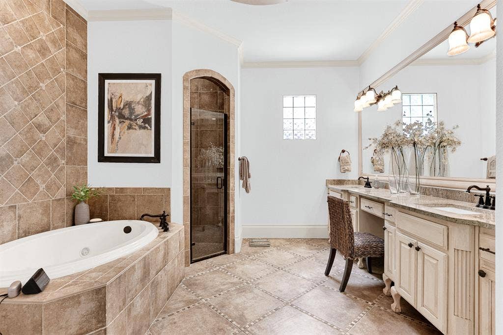 7032 PORTOBELLO Drive, Plano, TX 75024 An arched glass shower entry sits beside a jetted soaking tub framed by rich, diagonal stone tilework. Unwind with a warm, spa-like bath after a demanding workday.