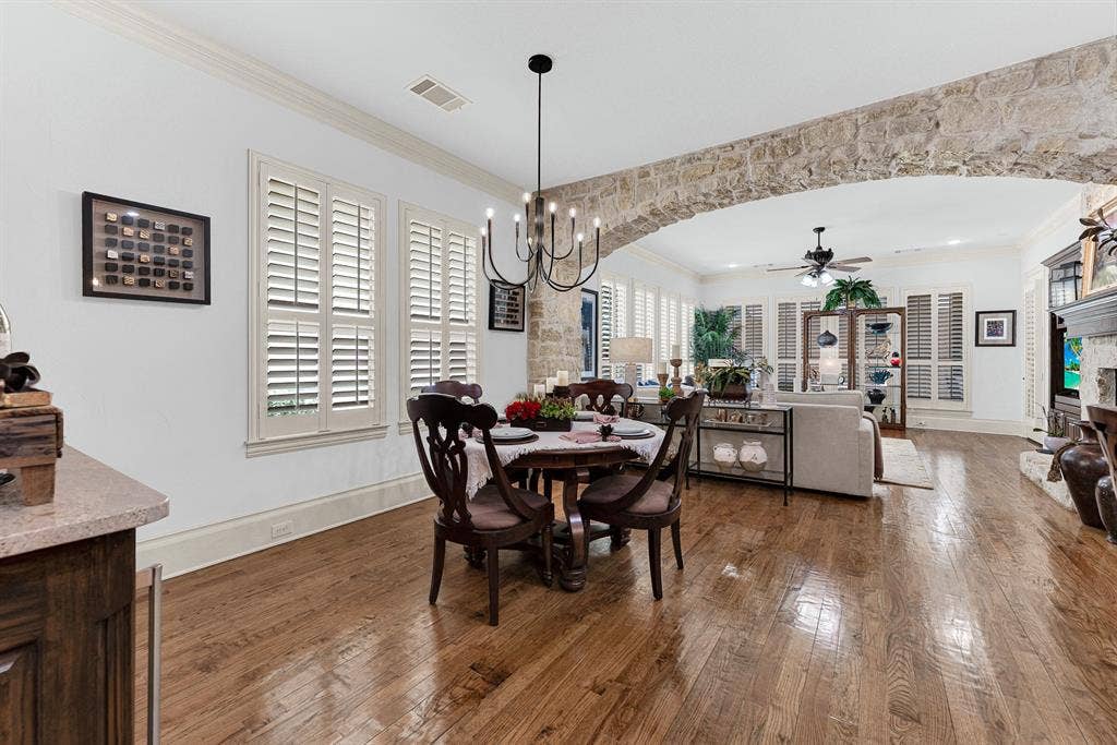 7032 PORTOBELLO Drive, Plano, TX 75024 An expansive stone archway naturally divides the casual dining space while allowing morning light to spill across gleaming hardwood floors. Gather here for a quiet, sunlit breakfast before the rest of the house stirs awake.