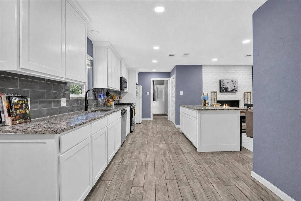 8117 Rush Street, Benbrook, TX 76116 Modern kitchen featuring white shaker cabinetry, granite countertops, stainless steel appliances, and a gray subway tile backsplash