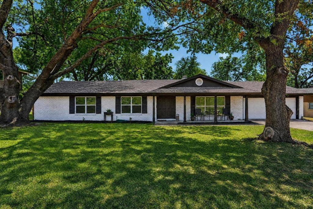 8117 Rush Street, Benbrook, TX 76116 Contemporary single-story residence featuring a clean-lined exterior with white stucco and dark trim, large multi-pane windows, and a covered front porch
