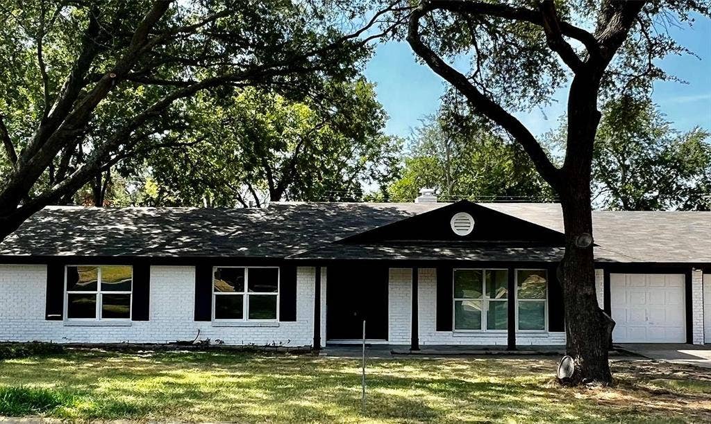 8117 Rush Street, Benbrook, TX 76116 White painted brick exterior with black shutters, multiple front-facing windows, and an attached two-car garage