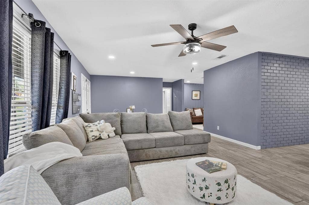 8117 Rush Street, Benbrook, TX 76116 Spacious living room featuring a sectional layout with neutral upholstery, wood-finish flooring throughout, and recessed ceiling lighting