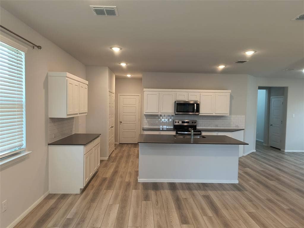 320 Leopold Trail, Greenville, TX 75402 Kitchen featuring white shaker cabinetry, dark countertops, a stainless steel microwave and range, a tile backsplash, and recessed lighting