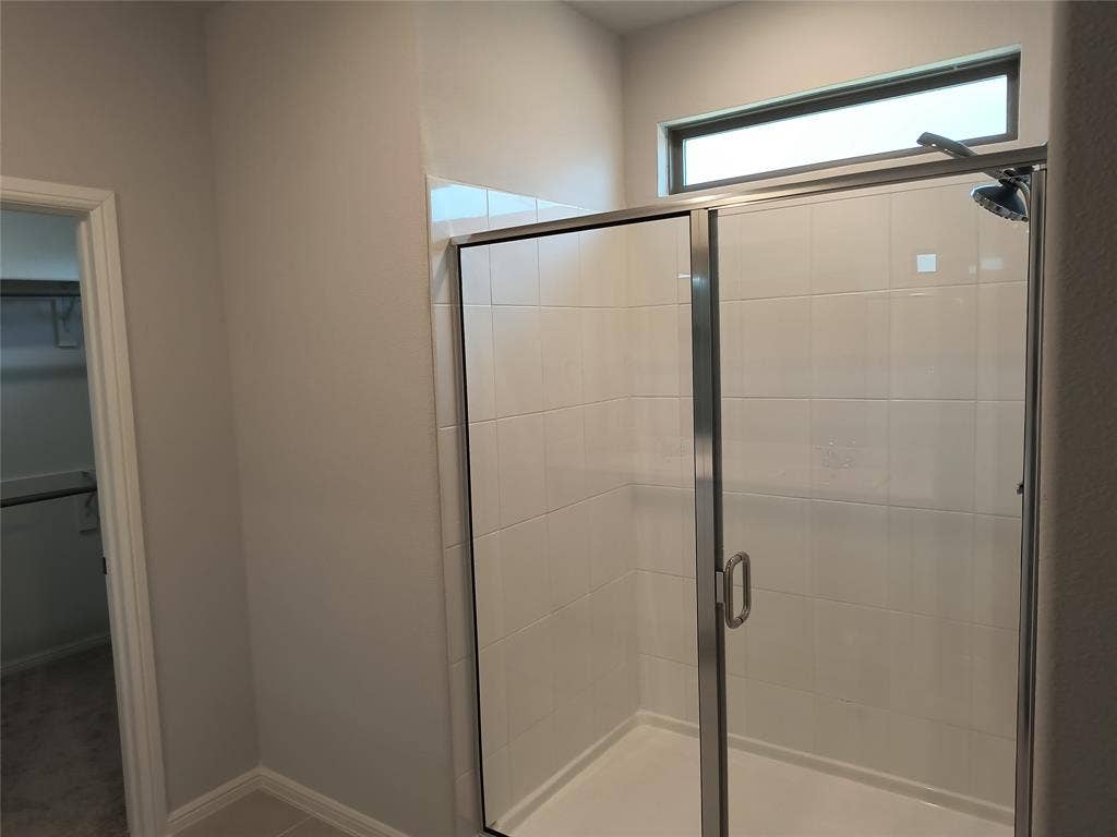 320 Leopold Trail, Greenville, TX 75402 Shower enclosure with white tile surround and a transom window