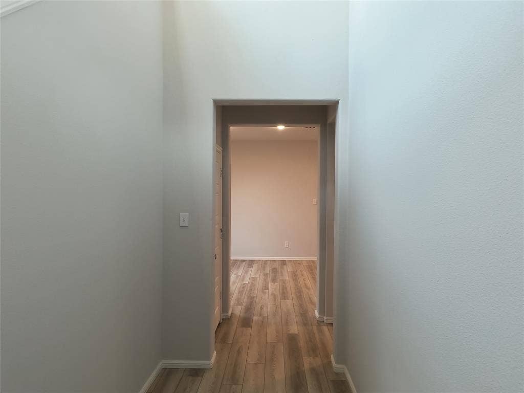 320 Leopold Trail, Greenville, TX 75402 Hallway featuring wood-finish flooring, light grey painted walls, and an arched doorway