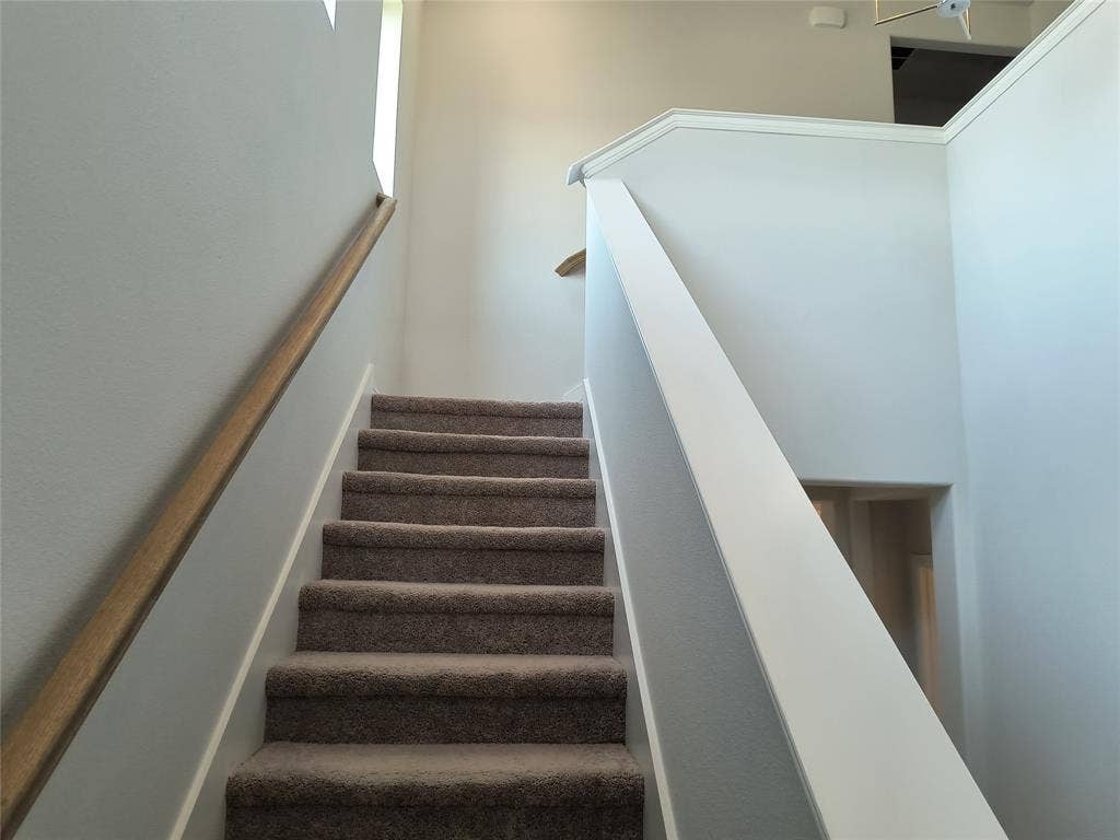 320 Leopold Trail, Greenville, TX 75402 Carpeted staircase with wood-finish handrail and painted balustrade