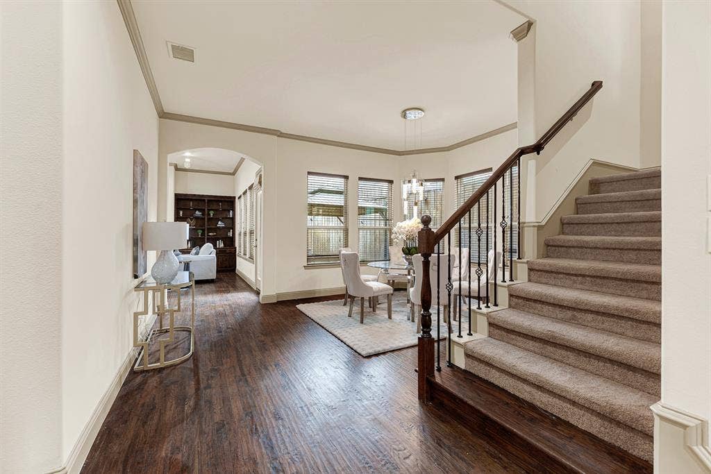 7013 BROOK FOREST Circle, Plano, TX 75024 The turned-spindle staircase rail gently guides sightlines beneath an arched entryway toward the formal dining space. Envision pouring celebratory toasts here while guiding guests seamlessly toward a festive holiday dinner.