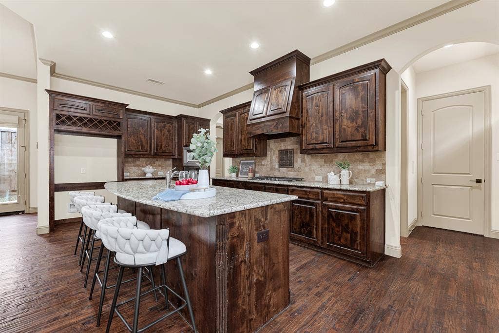 7013 BROOK FOREST Circle, Plano, TX 75024 Fluted wooden corner millwork on the island and sweeping arched entryways lend refined architectural texture to the workspace. Envision setting out an abundant charcuterie spread here as weekend entertaining naturally kicks into gear.