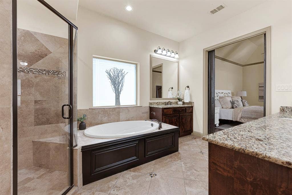 7013 BROOK FOREST Circle, Plano, TX 75024 A paneled wainscot surround encases the deep drop-in garden tub, bathed in soft daylight from the frosted privacy window. Unwind with an aromatherapy bubble bath here, soaking away tension while surrounded by spa-inspired serenity.