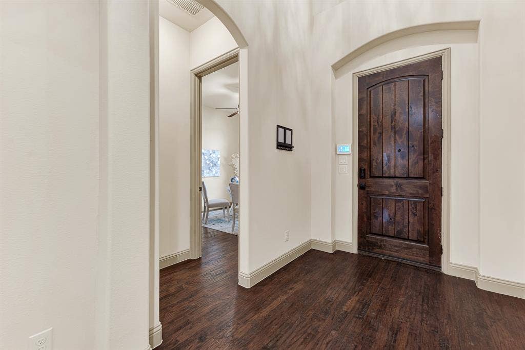 7013 BROOK FOREST Circle, Plano, TX 75024 A substantial knotty-wood entry door sits recessed beneath a graceful arched niche, pairing rich grain textures with sweeping foyer lines. It marks the spot where you warmly greet arriving friends, setting an easy, hospitable mood the second they arrive.