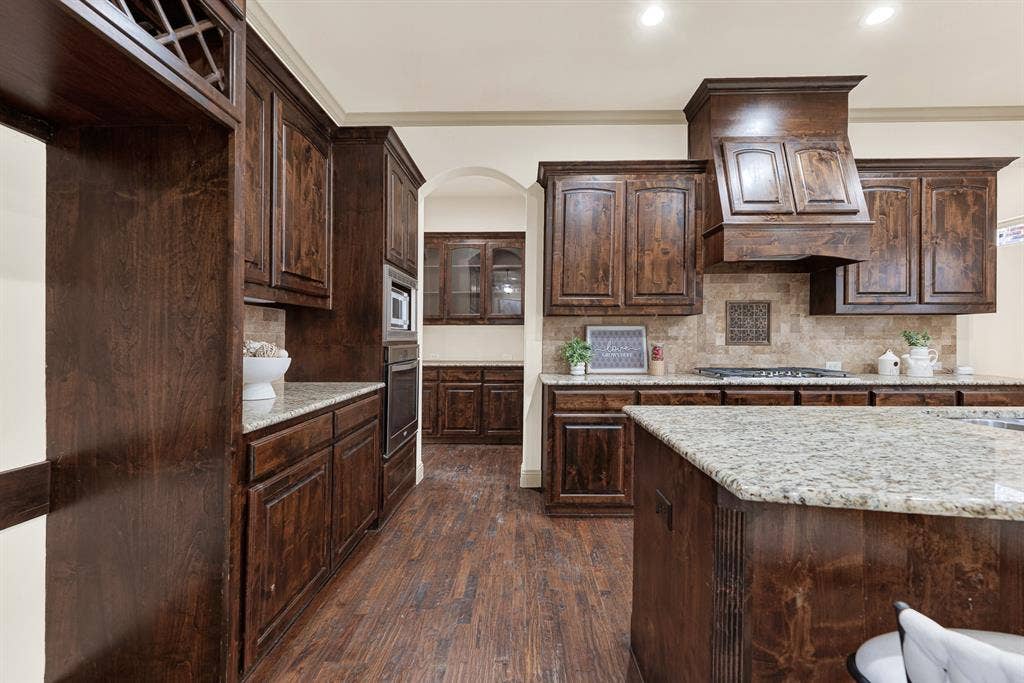 7013 BROOK FOREST Circle, Plano, TX 75024 Built-in wine cubbies frame the upper alcove, leading the eye toward the arched butler’s pass-through. It’s built for quiet evening tastings, pouring a vintage cabernet straight from the rack before guests arrive.