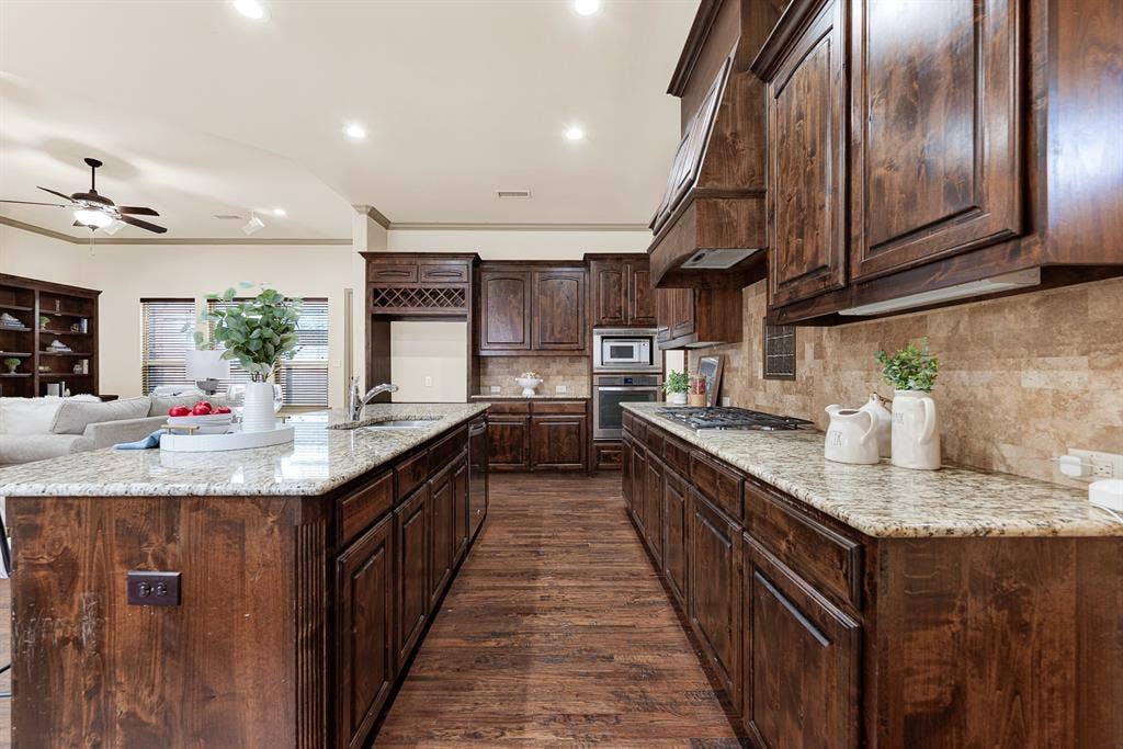 7013 BROOK FOREST Circle, Plano, TX 75024 Deep granite worktops flank the recessed gas cooktop, providing generous culinary prep zones along the main aisle. Feel the joy of simmering fragrant, slow-cooked sauces while easily conversing across the open prep space.