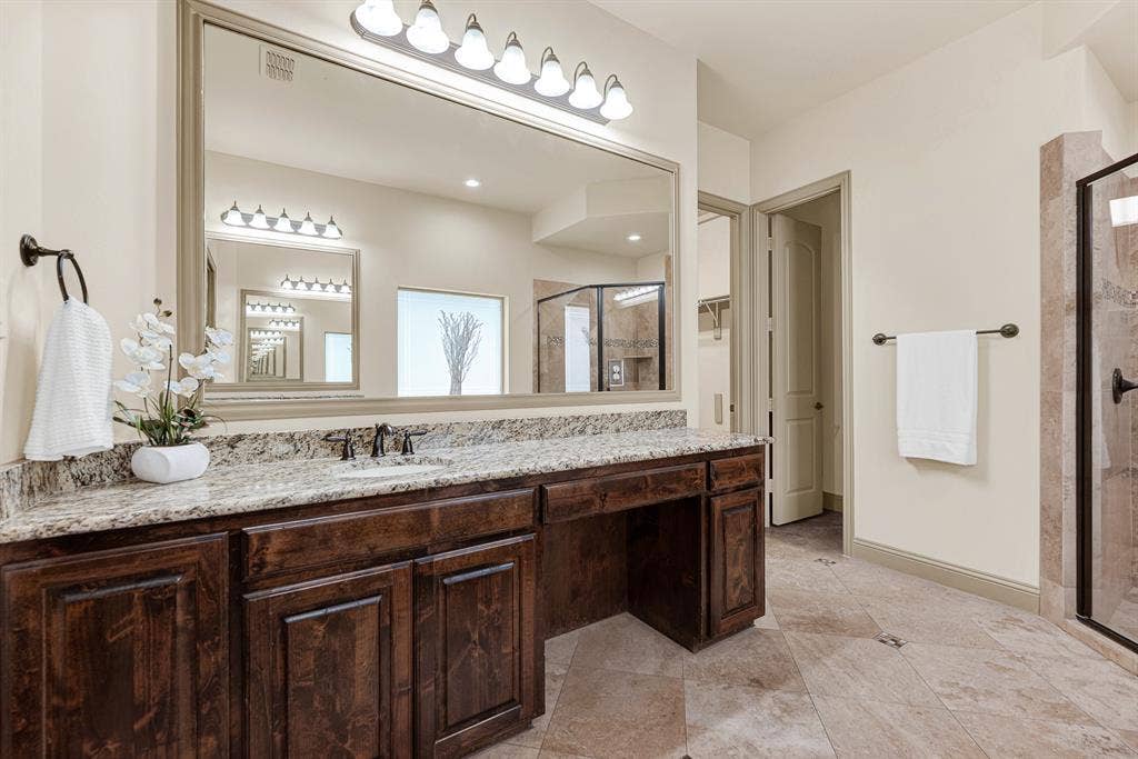 7013 BROOK FOREST Circle, Plano, TX 75024 A multi-globe vanity bar illuminates the framed full-width mirror and integrated makeup knee space. It makes preparing for a night on the town feel relaxed and organized, with dedicated seating for cosmetics and grooming.