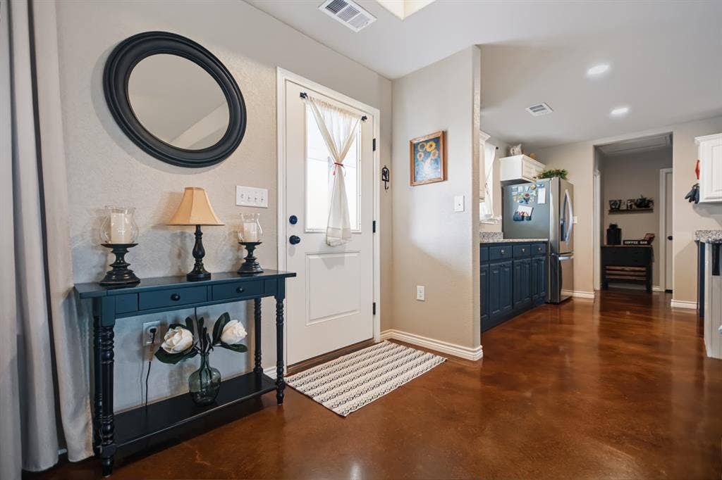 2433 Trlica Road, West, TX 76691 Back DoorRichly toned flooring extends throughout, complemented by a white entry door, recessed lighting, and a kitchen featuring dark-toned cabinetry and light-toned countertops