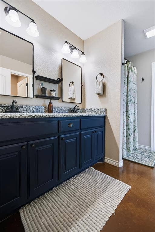 2433 Trlica Road, West, TX 76691 Double vanity with dark blue cabinetry and granite countertops