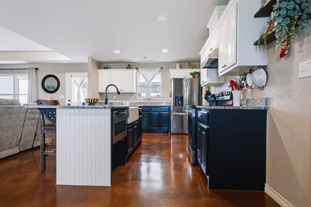 2433 Trlica Road, West, TX 76691 Kitchen with two-tone cabinetry, a central island, a farmhouse sink, stainless steel appliances, and a wood-finish floor