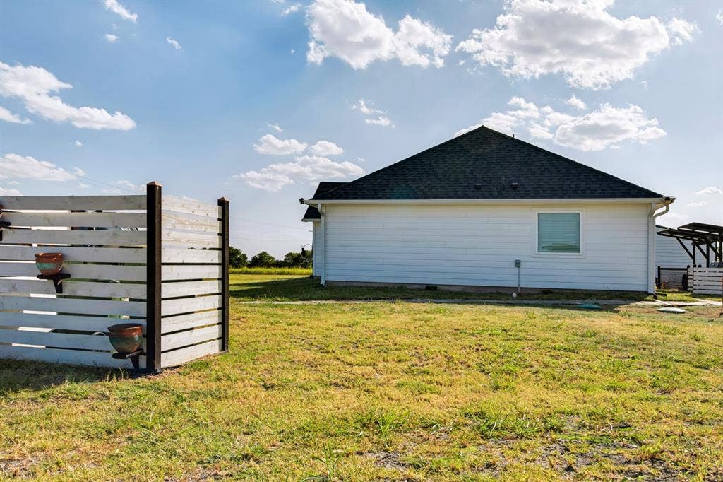 2433 Trlica Road, West, TX 76691 Expansive outdoor space featuring a white slatted fence, a dark shingle roof, white siding, and a single pane window
