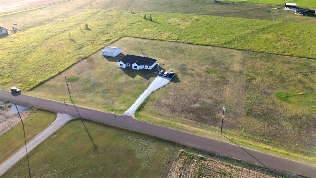 2433 Trlica Road, West, TX 76691 Expansive green land surrounding a residence with a white exterior, dark roof, and a gravel driveway