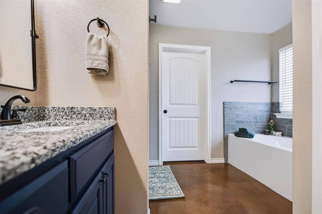 2433 Trlica Road, West, TX 76691 Bathroom featuring a white bathtub, tiled wainscoting, and wood-finish flooring