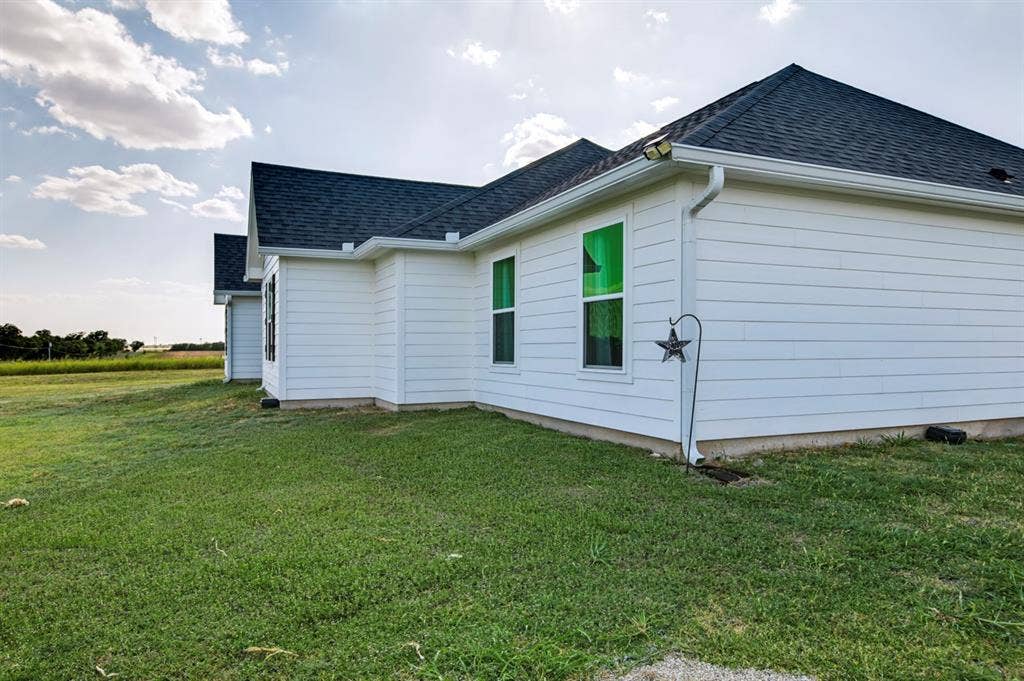 2433 Trlica Road, West, TX 76691 White siding exterior with a dark shingle roof and white gutters